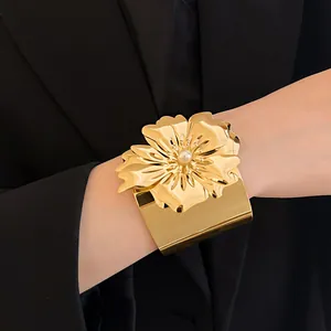 Primer plano de un llamativo brazalete de flor dorada combinado con una chaqueta negra elegante.