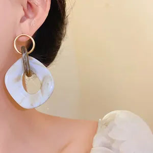 Dettaglio orecchini geometrici in acrilico con motivo marmorizzato vintage e cerchio
