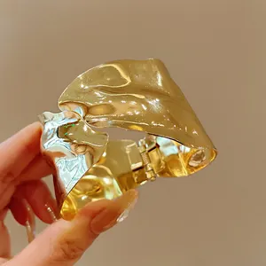 Detailed close-up of a minimalist irregular geometric metal bangle with a polished gold finish