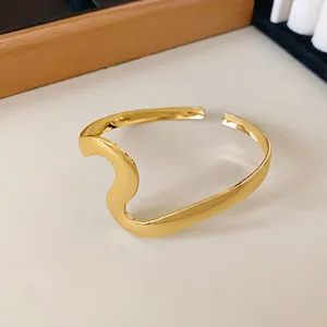 Vista macro de brazalete abierto ondulado dorado con acabado pulido