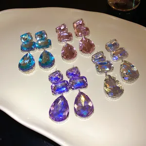 Primo piano di orecchini pendenti in cristallo a goccia e quadrati molto scintillanti