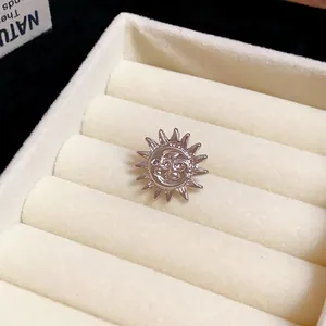 Detailed view of a silver-toned metal sun flower ear clip in a white jewelry box