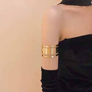 Vista detallada de un elegante brazalete ancho de metal dorado en una modelo con guantes