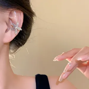 Close-up detail of a silver metal starfish ear cuff on an ear, showing elegant fashion style.