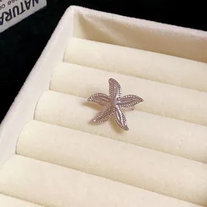 Close-up of a silver-toned metal starfish ear clip on a cream jewelry tray