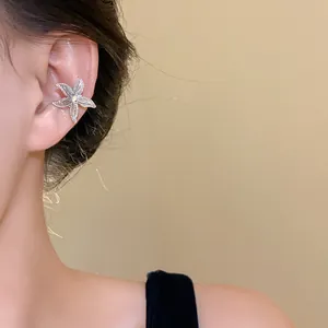 Detailed shot of a silver starfish-shaped ear cuff worn on the ear
