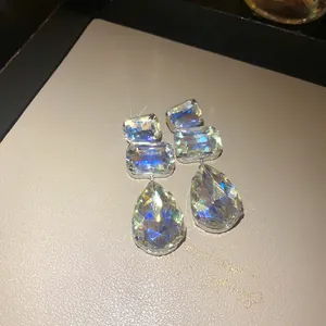 Primo piano di scintillanti orecchini di cristallo a goccia e rettangolari con ago d'argento