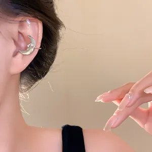 Close-up of a silver crescent moon ear cuff with a face design worn on the ear
