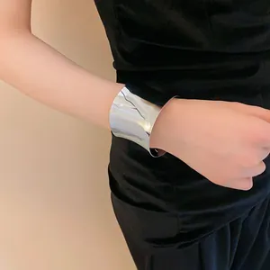 Primer plano de un brazalete minimalista ancho de plata ondulado en la muñeca mujer