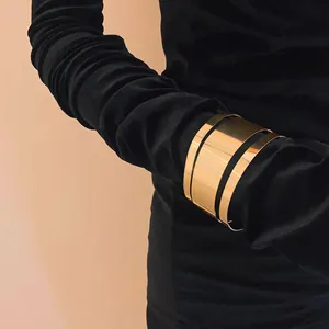Primer plano de un elegante brazalete dorado de varias capas sobre una manga negra