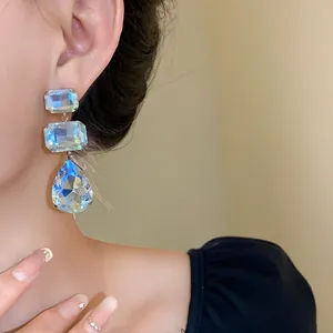 Primo piano degli orecchini a nappa con cristalli quadrati e a forma di goccia.
