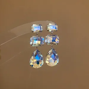 Dettaglio degli orecchini in cristallo iridato a forma di quadrato e goccia.