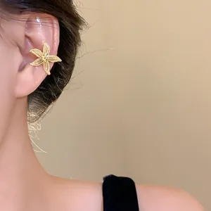 Detailed close-up of a stylish golden starfish ear clip on an Asian model's ear