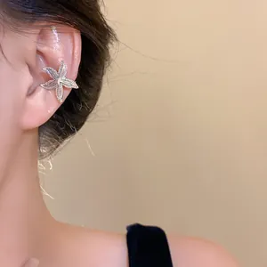 Detail view of silver starfish ear cuff worn on model's ear showing delicate texture