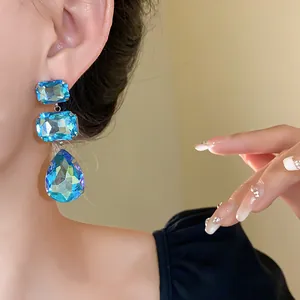 Dettaglio ravvicinato di eleganti orecchini pendenti in cristallo blu su una modella