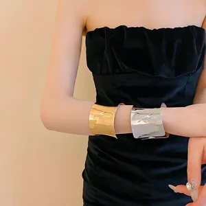 Elegantes brazaletes anchos en oro y plata mostrados en la muñeca de una modelo