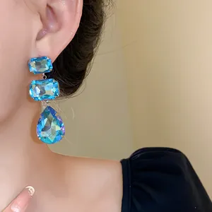 Dettaglio ravvicinato di orecchini a goccia in cristallo blu con perni in argento pregiato.