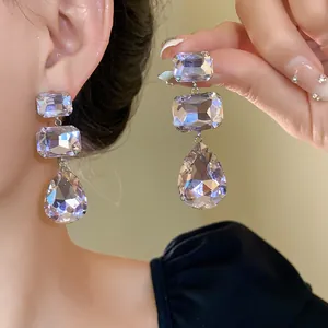 Dettaglio di orecchini a più livelli con cristalli rettangolari e a goccia per look lusso