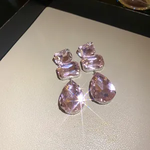 Dettaglio ravvicinato di eleganti orecchini in cristallo rosa con luce scintillante