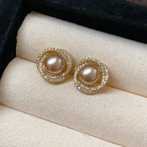 Exquisite detail of gold-plated stud earrings featuring champagne pearls and zircon halo