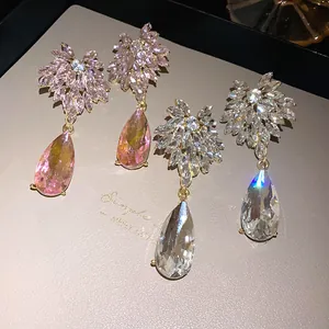 Close-up of elegant flower stud earrings with pear-shaped rhinestone drops in pink and white
