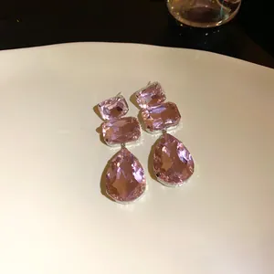 Dettaglio macro di eleganti orecchini in cristallo rosa su un piatto decorativo