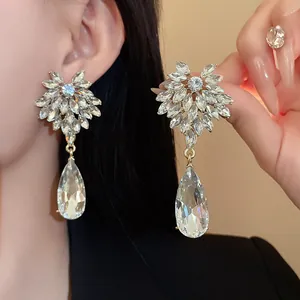 Close-up of crystal flower and teardrop earrings worn by model showing intricate details.