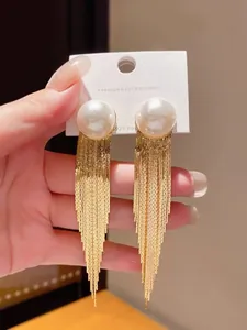 Macro detail of gold tassel earrings with elegant white pearl and S925 silver post.