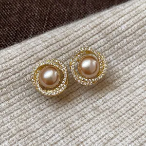Close-up of elegant gold-plated stud earrings featuring a champagne pearl and zircon halo.