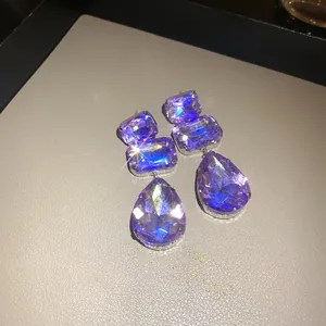 Dettaglio di orecchini di cristallo viola con pietre quadrate e a forma di goccia