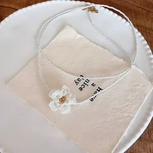 Detailed macro shot of a white beaded camellia flower pendant necklace on a plate.
