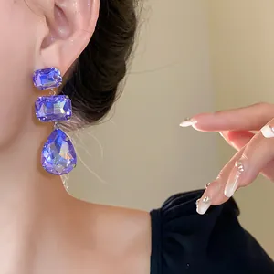 Dettaglio ravvicinato di eleganti orecchini a goccia in cristallo viola su modella
