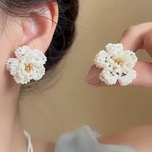 Close-up of elegant handmade beaded camellia flower earrings with gold center.