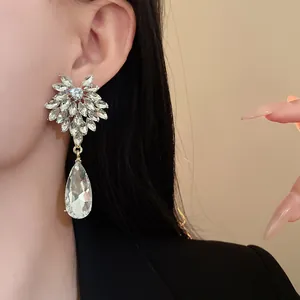 Close-up of elegant sparkling flower crystal earrings with water drop pendant on model
