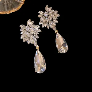 Elegant silver needle drop earrings featuring sparkling flower-shaped crystals and large teardrop stones.