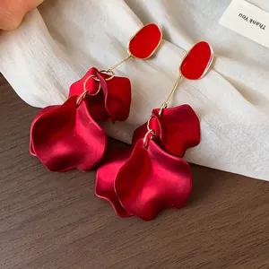 Detail shot of elegant red acrylic flower petal earrings with gold-toned metal accents