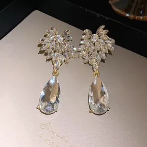 Close-up of sparkling crystal flower and teardrop earrings with silver needles.