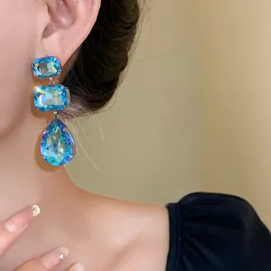 Primo piano di eleganti orecchini pendenti a tre strati in cristallo blu con goccia