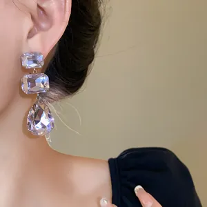 Primo piano di lussuosi orecchini in argento con cristalli quadrati e a goccia brillanti.