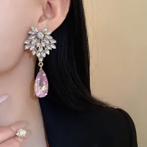 Close-up detail of elegant floral earrings with a pink crystal water drop on model