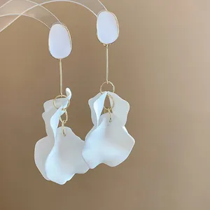 Macro view of elegant white acrylic petal drop earrings with golden needle details.