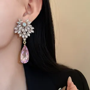 Detail shot of elegant floral rhinestone drop earrings featuring a pink teardrop crystal.