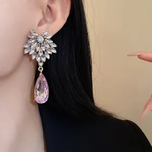 Detailed view of elegant silver needle flower earrings with pink teardrop crystals on model
