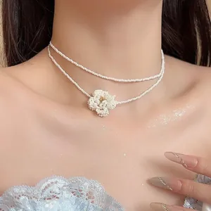 Detailed close-up of an elegant white beaded camellia flower choker necklace on a model