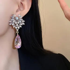 Detailed view of floral silver earrings with a large pink teardrop gemstone