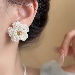 Handmade elegant white beaded camellia flower stud earrings shown as a macro detail on ear
