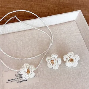 Detailed view of white beaded camellia jewelry set with necklace and earrings