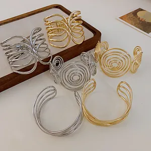 Variety of metallic gold and silver open cuff bracelets in different artistic styles.