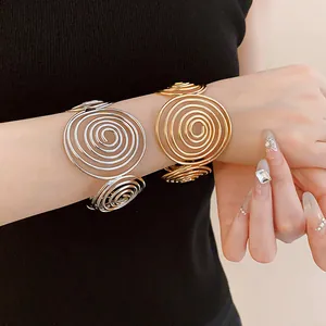 Detailed view of gold and silver spiral metal bangles worn on a wrist.