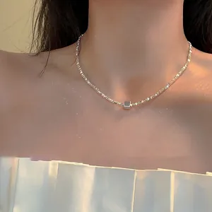 Detailed close-up of a silver geometric cube pendant necklace on a model's neck
